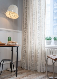 Detail of French vintage linen curtain with black geometric diamond print in warm home setting