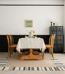 Close-up of beige tablecloth featuring yellow floral embroidery and dense fringe tassels