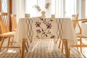 Close-up of floral embroidery and fringe tassels on a cream cotton linen tablecloth