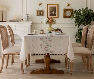 Detail of floral embroidery and fringe tassels on a cream French style tablecloth