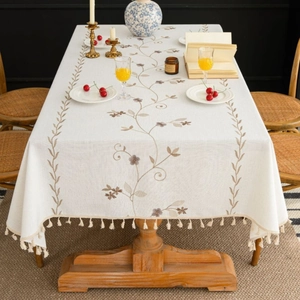 Linen table cloth with brown floral embroidery and beige tassel trim in home setting