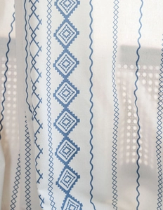 Detail of blue geometric print window curtain with tassel trim and textured fabric