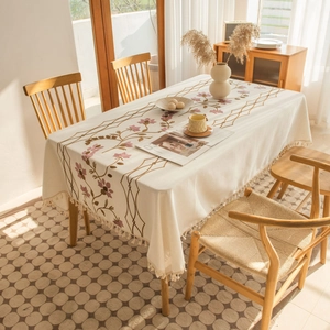 Detail of floral embroidery and fringe trim on off-white cotton linen tablecloth