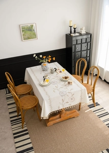 Close-up of floral embroidery and beige tassel fringes on a cotton linen tablecloth
