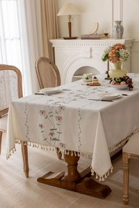 Detailed cream floral embroidery and tassel fringe on a French linen rectangular tablecloth