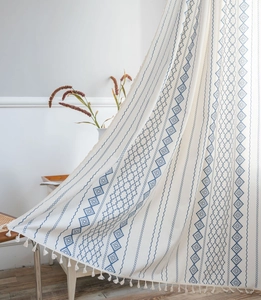 Detail of blue geometric embroidery on cream fabric with elegant tassel trim