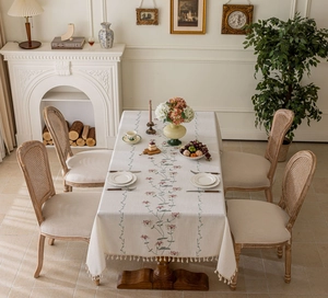 Close-up of cream rectangular tablecloth with floral embroidery and tassel fringe