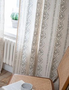 Detail of beige linen curtain with black geometric patterns in a cozy home setting