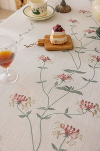 Detail of floral embroidery on cream linen tablecloth with vintage elegant tassel edges