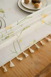 Close-up of floral embroidery and fringe tassels on Nordic style linen tablecloth