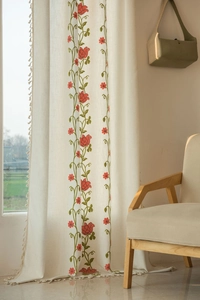 Detail view of beige cotton-linen curtain with red floral embroidery and tassel fringe edges
