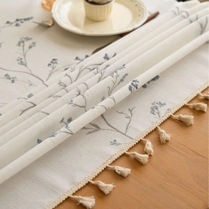 Rustic off-white tablecloth with floral lilac embroidery and fringe tassels for dining tables