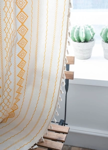 Detail of yellow geometric pattern and tassels on bohemian light filtering curtains