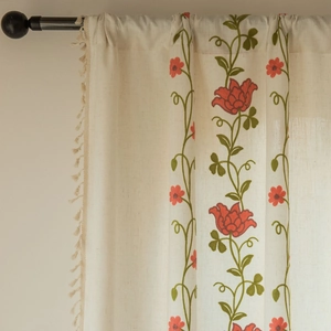 Detail of beige linen curtain with floral embroidery and elegant tassel fringe