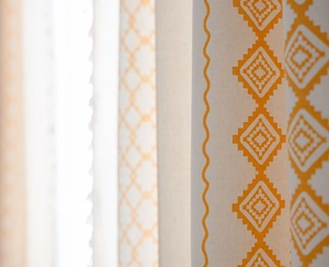 Detailed texture of beige linen curtain with yellow geometric print and tassels