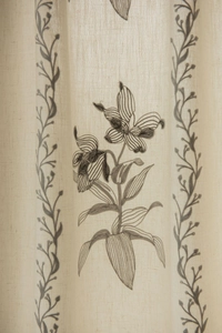 Dettaglio del ricamo floreale su tende beige in simil lino semi-trasparenti