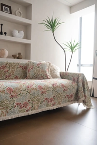 Close-up of floral jacquard sofa cover with pink blossoms and white fringe tassels