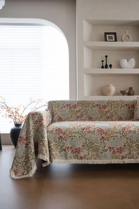 Close-up of pink floral pattern and fringe tassels on a thick beige sofa cover blanket