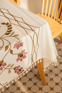 Detailed view of floral embroidery and fringe tassels on a linen-style tablecloth