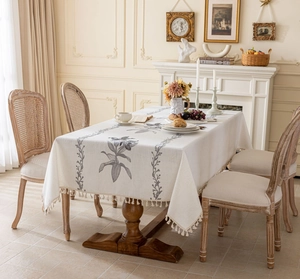 Gros plan sur une nappe rectangulaire crème avec broderie florale et bords à franges
