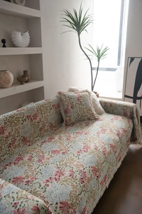 Close-up of pink floral jacquard sofa throw with elegant cream fringe tassels