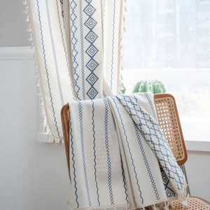Bohemian blue geometric pattern curtain with tassels draped on a vintage rattan chair