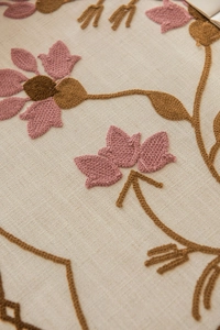 Detail of pink floral embroidery on beige cotton linen fabric with high texture