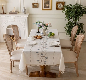 Detail of French floral embroidery and elegant tassels on a cream linen tablecloth