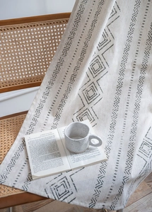 Close-up of geometric pattern on linen fabric over a rattan chair with a book