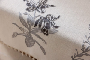 Détail de la nappe en lin beige avec broderie florale et bordure à franges élégante