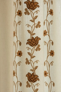 Close-up of beige fabric featuring classic dark brown floral embroidery and rich texture