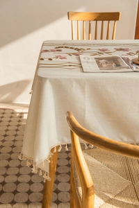 Detail of floral embroidery and beige tassels on a cotton linen rectangular tablecloth