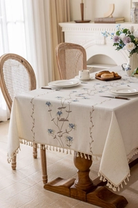 Close-up of elegant floral embroidery and tassel fringe on cream French tablecloth