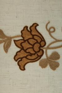 Detail of elegant brown floral embroidery on beige linen curtain with precise stitching