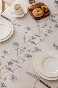 Detail of floral embroidery on cream linen tablecloth with tassels in lifestyle setting