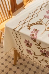 Close-up of floral embroidery and beige tassels on a cotton linen tablecloth