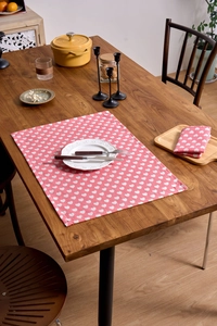 Detail of pink heart-print fabric napkin with visible texture on a wooden dining table