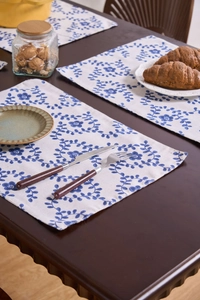 Close-up of blue floral cotton linen placemats on a rustic dark wood dining table
