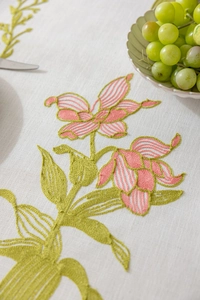 Détail de broderie florale rose sur nappe en lin beige avec des feuilles vertes