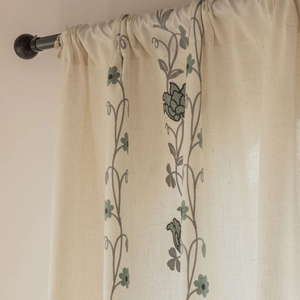 Close-up of beige faux linen curtain with elegant floral embroidery and rod pocket