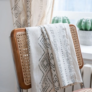 Bohemian linen table runner with black geometric tribal patterns on a beige wood chair