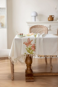 Détail d'une broderie florale élégante et de pompons sur une nappe rectangulaire