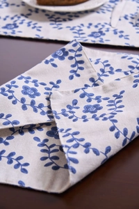 Detalle de mantel individual de lino con flores azules, textura y bordes cosidos