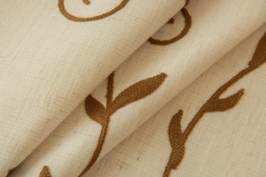 Macro detail of beige cotton linen fabric featuring elegant dark brown leaf embroidery