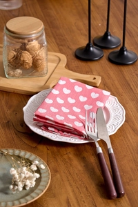 Close-up of pink heart-patterned napkins folded on a plate for a rustic table setting