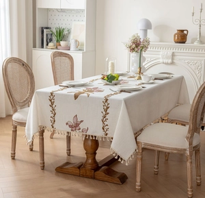 Détail de la broderie florale rose et des franges sur nappe en lin de coton beige