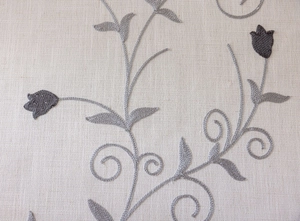 Macro detail of American pastoral tablecloth with grey floral embroidery and linen texture