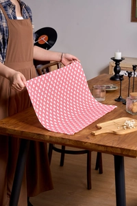 Close-up of pink fabric napkin with heart print pattern held over wooden table