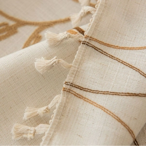 Beige floral embroidery tablecloth with tassel edges and rustic woven textile texture