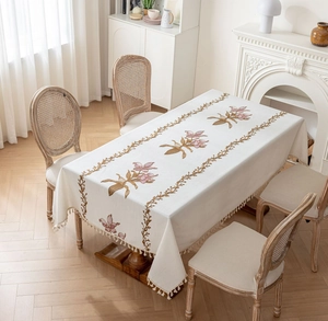 Gros plan de la nappe beige rectangulaire avec broderie florale rose et franges